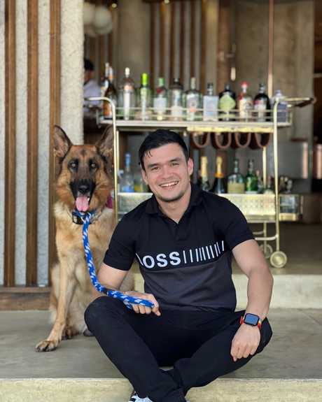 Sergio sitting on a step next to Maximus, his German Shepherd, at a bar in Medellín