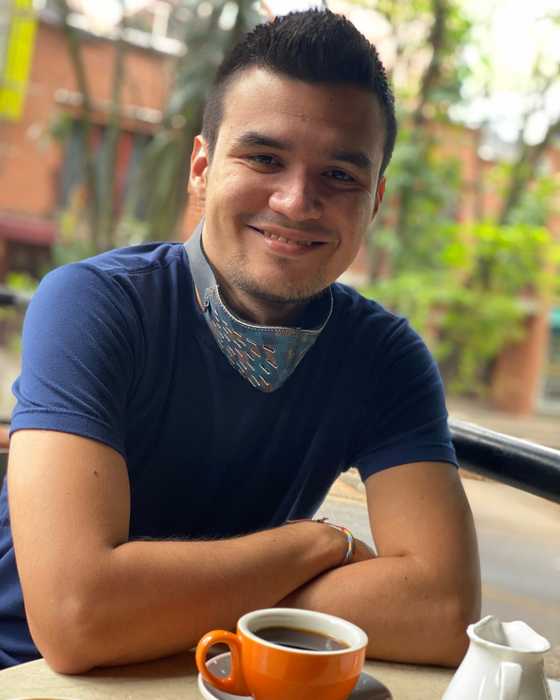 Sergio smiling at a café table with an espresso, Medellín